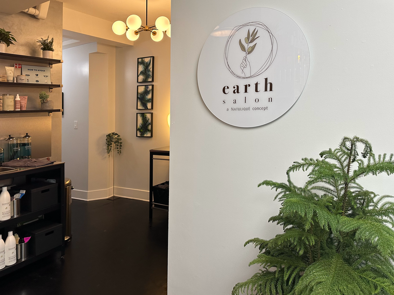 Earth Salon retail area inside DaneStyles Hair Artistry, with the Natulique concept wall sign and shelves of organic hair products