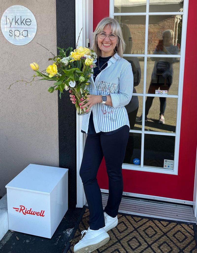 Lone Holt, owner of DaneStyles Hair Artistry, holding flowers outside Lykke Spa in Snohomish