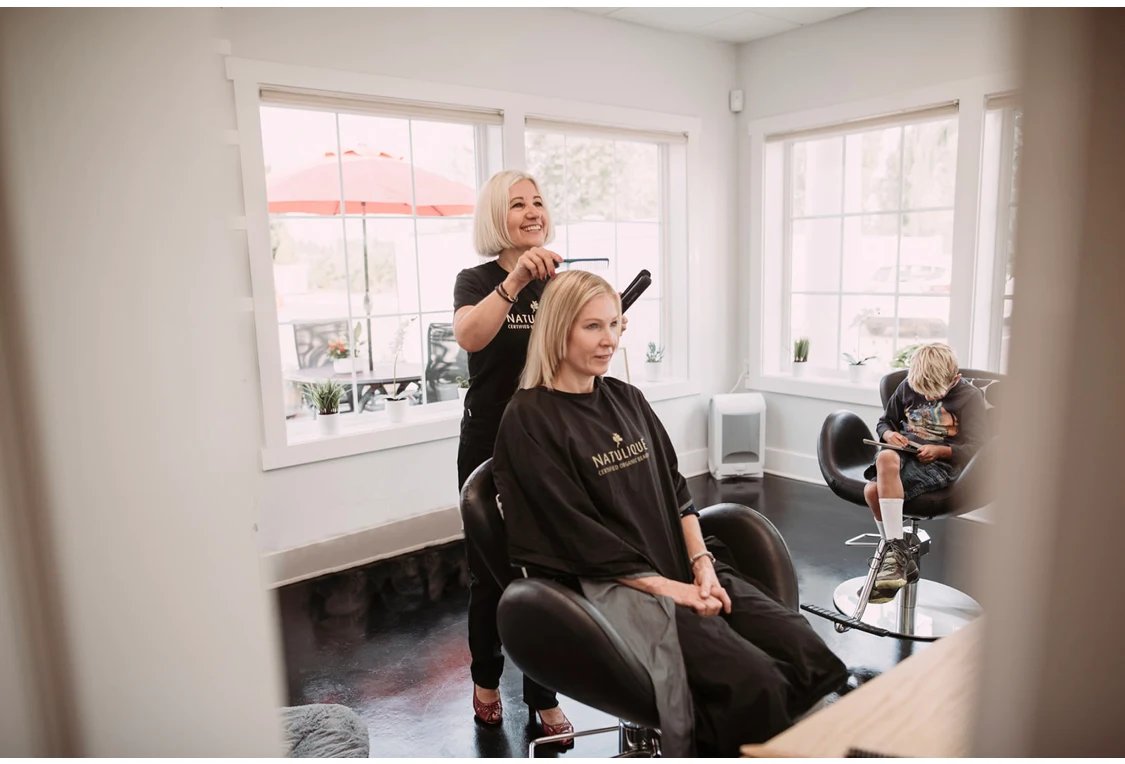 Lone Holt styling a client's hair at DaneStyles Hair Artistry salon in Snohomish, WA using Natulique organic products