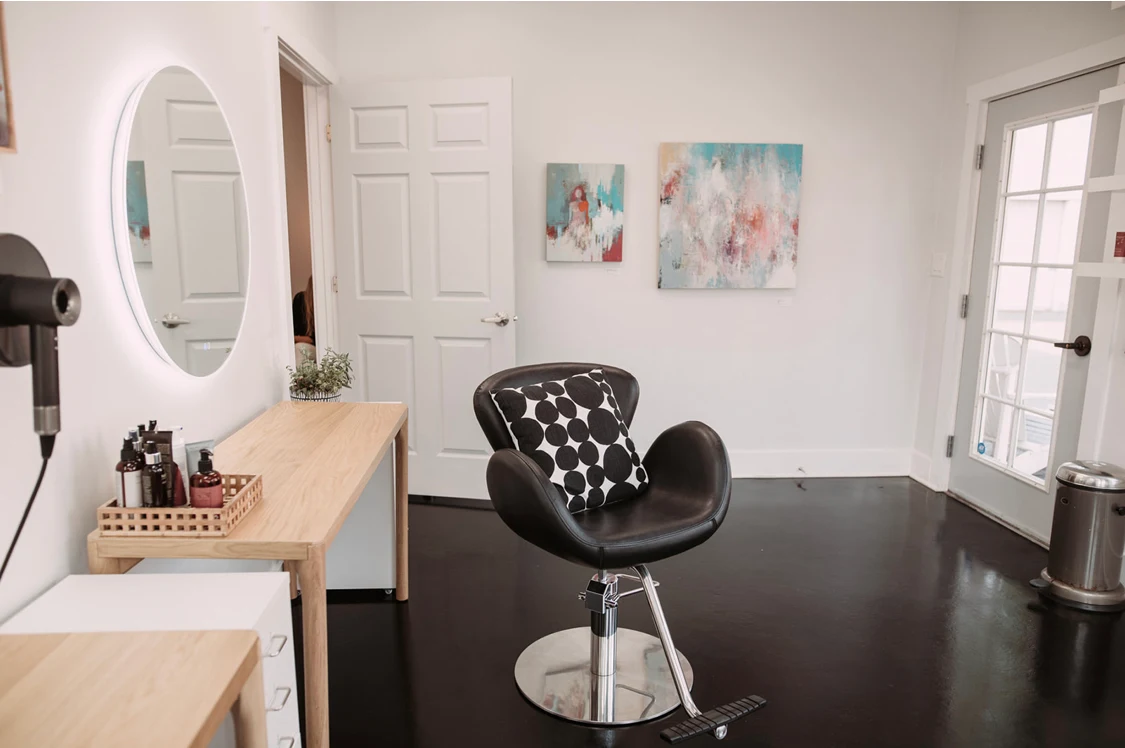 Styling station with a leather chair, lighted mirror, and local artwork at DaneStyles Hair Artistry in Snohomish, WA
